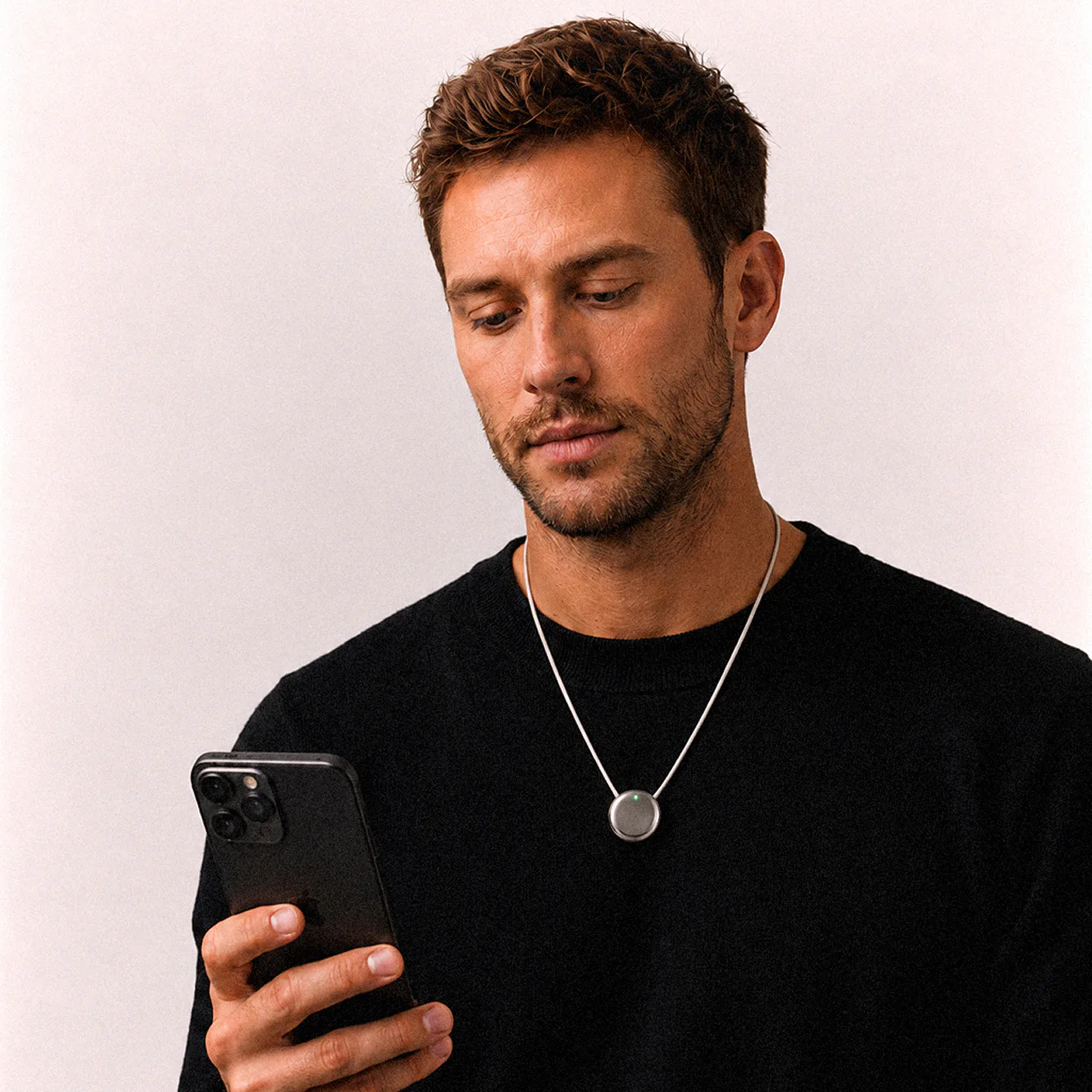 A man wearing Pebb, reading his reflections in the app on his phone
