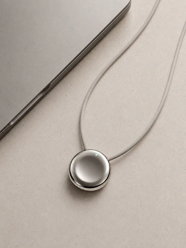 The Pebb pendant lying next to a laptop